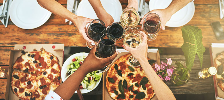 a group of people putting their glasses with wine together with food on the table
